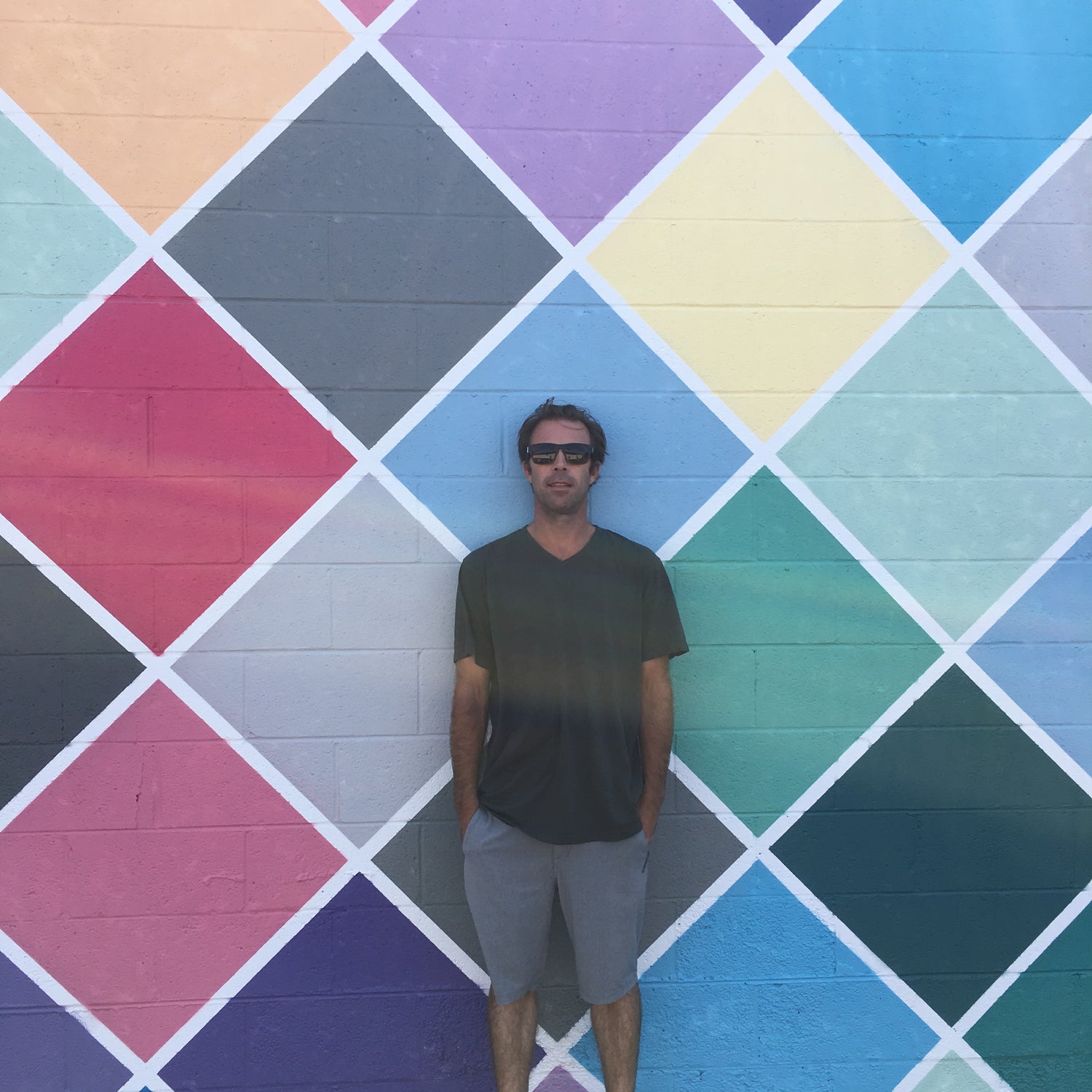 Billy Pease from Burnt Module standing in front of a large colorful mural he painted in San Diego.